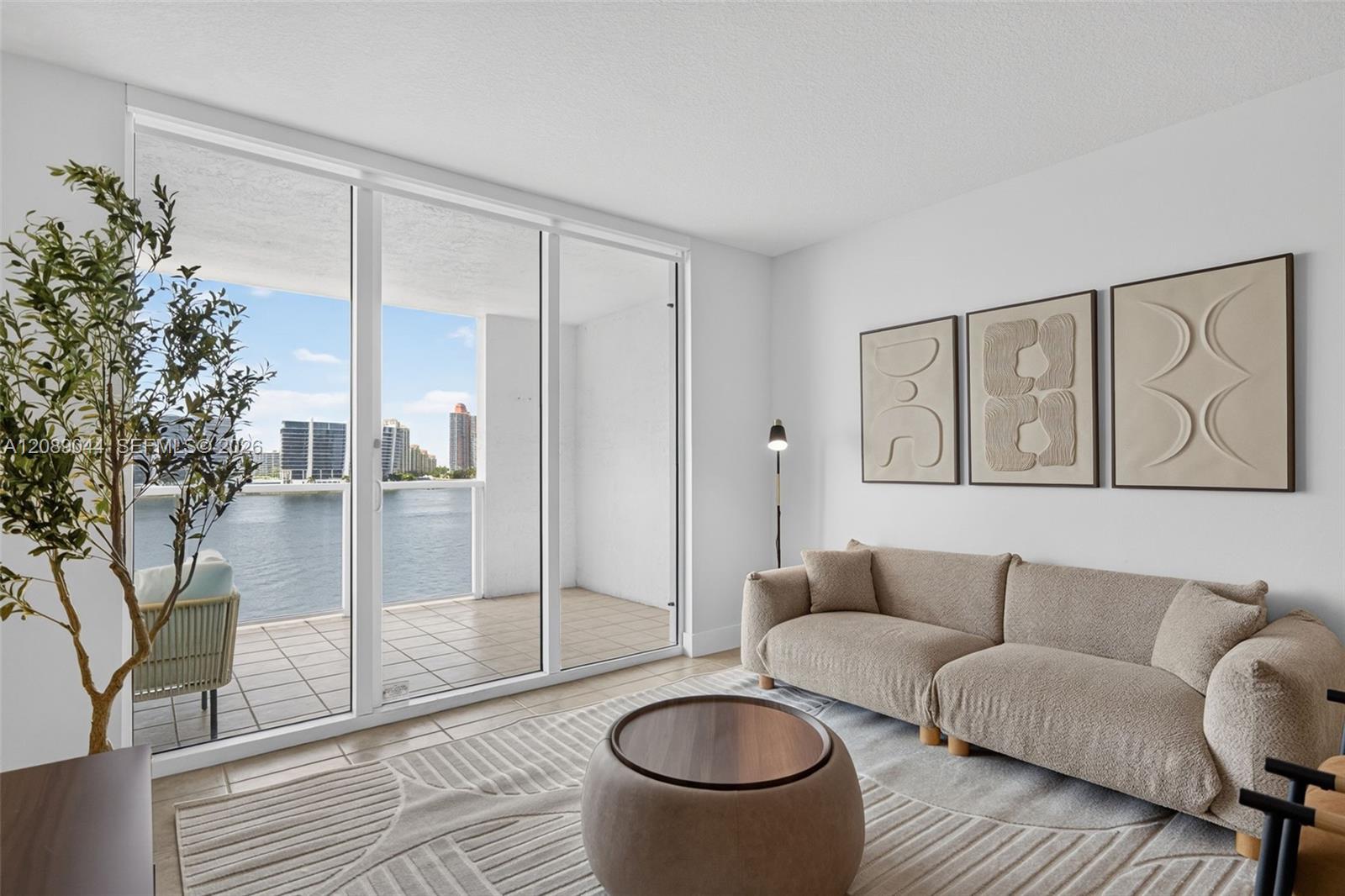 Living room with a beige sectional and balcony doors overlooking the water.