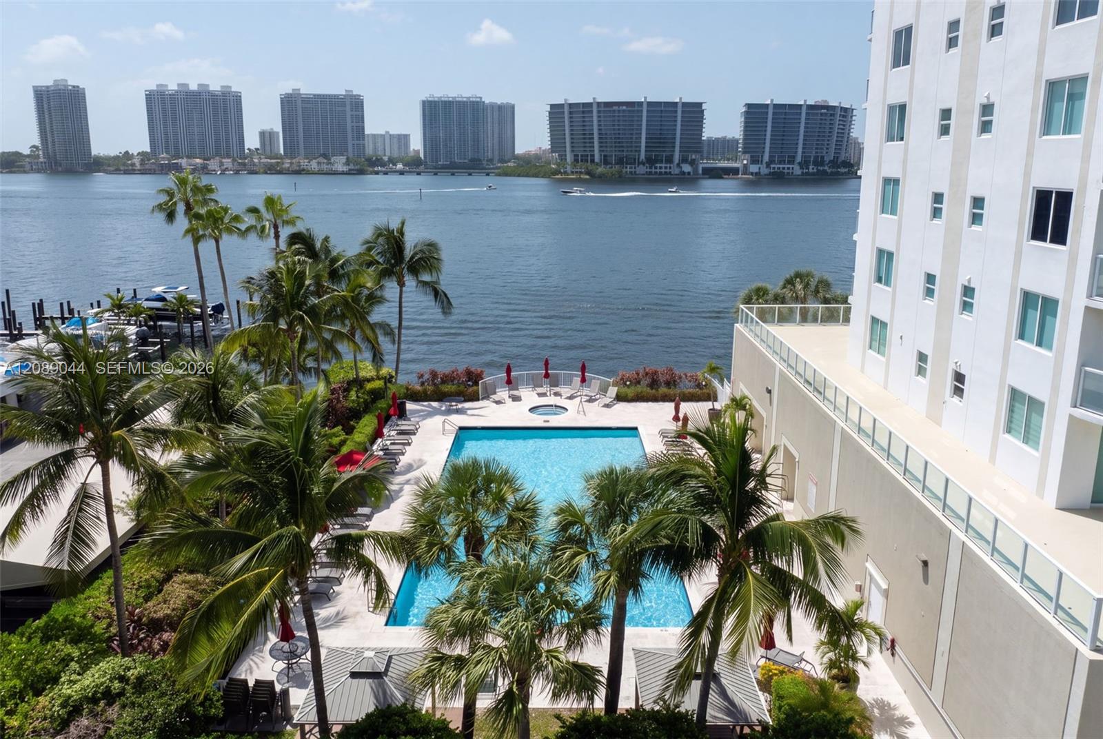 Condominium pool deck with palm trees overlooking the bay and waterfront high-rises.