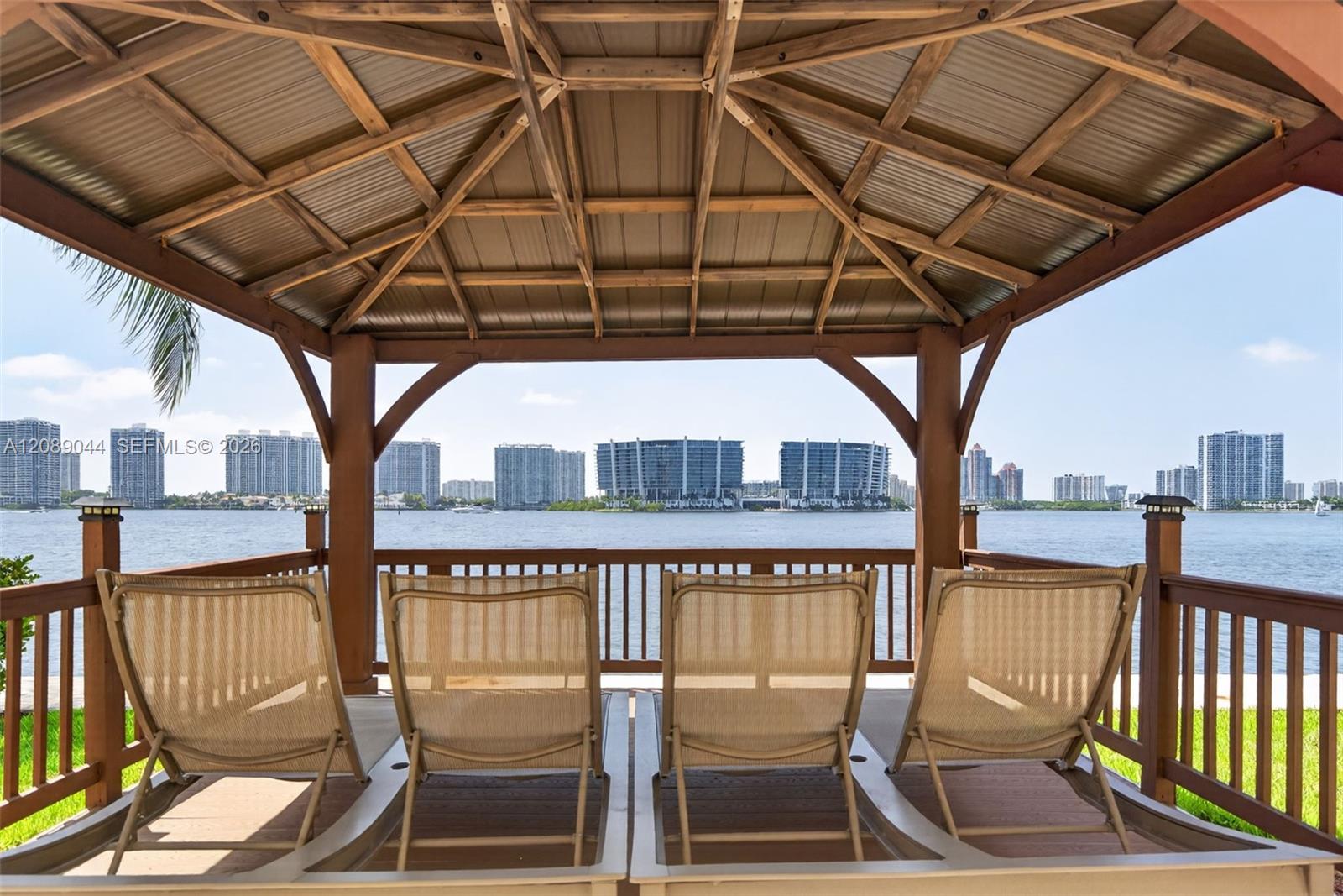 Covered waterfront patio with four lounge chairs overlooking the bay and city skyline.