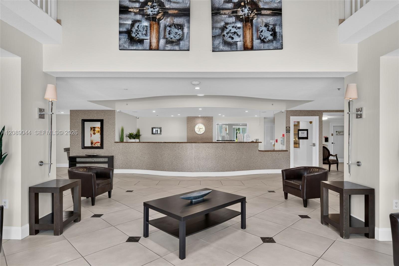Condominium lobby with a curved reception desk and dark leather seating.