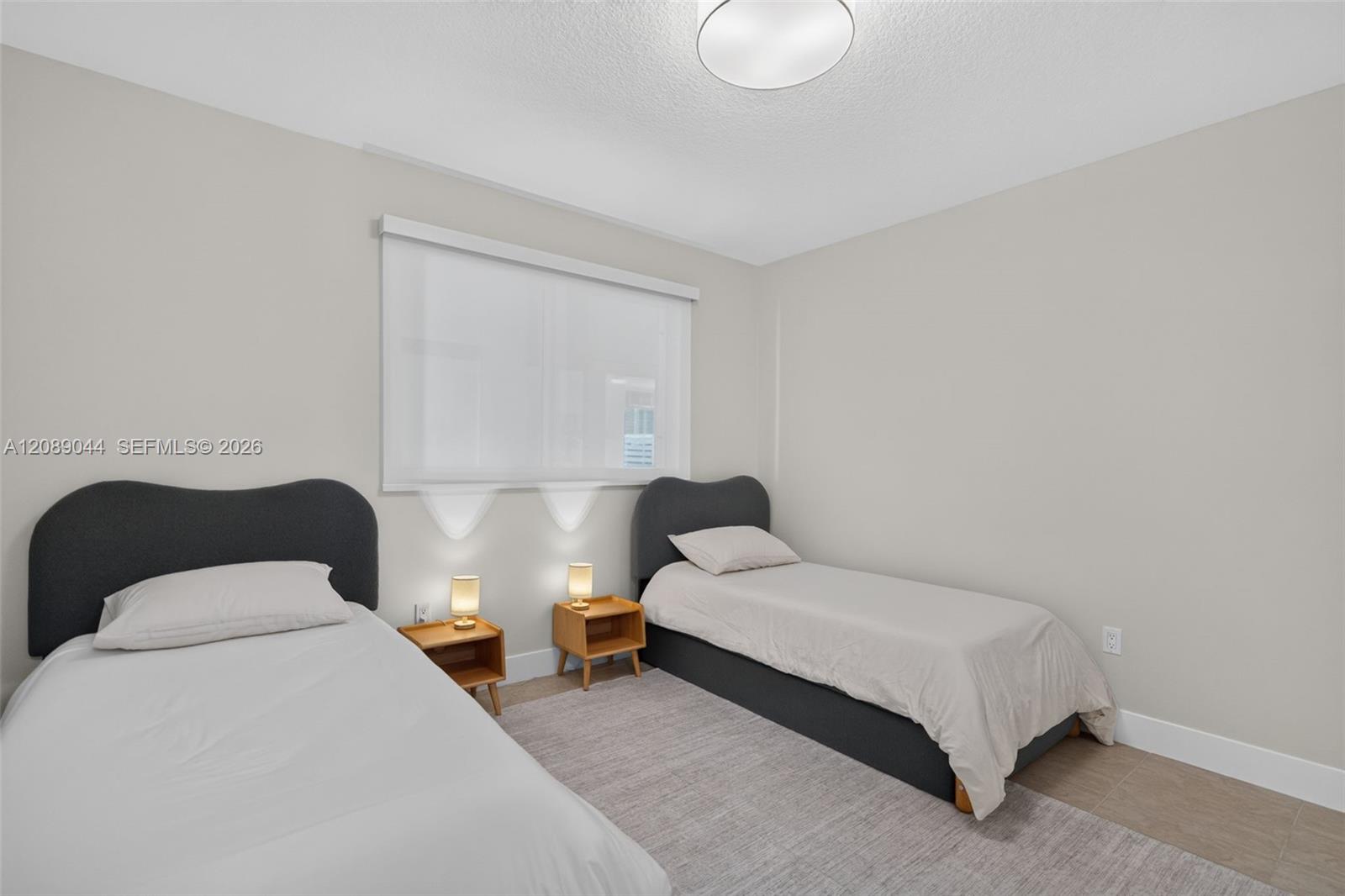 Bedroom with two single beds, dark headboards, and matching wooden nightstands.