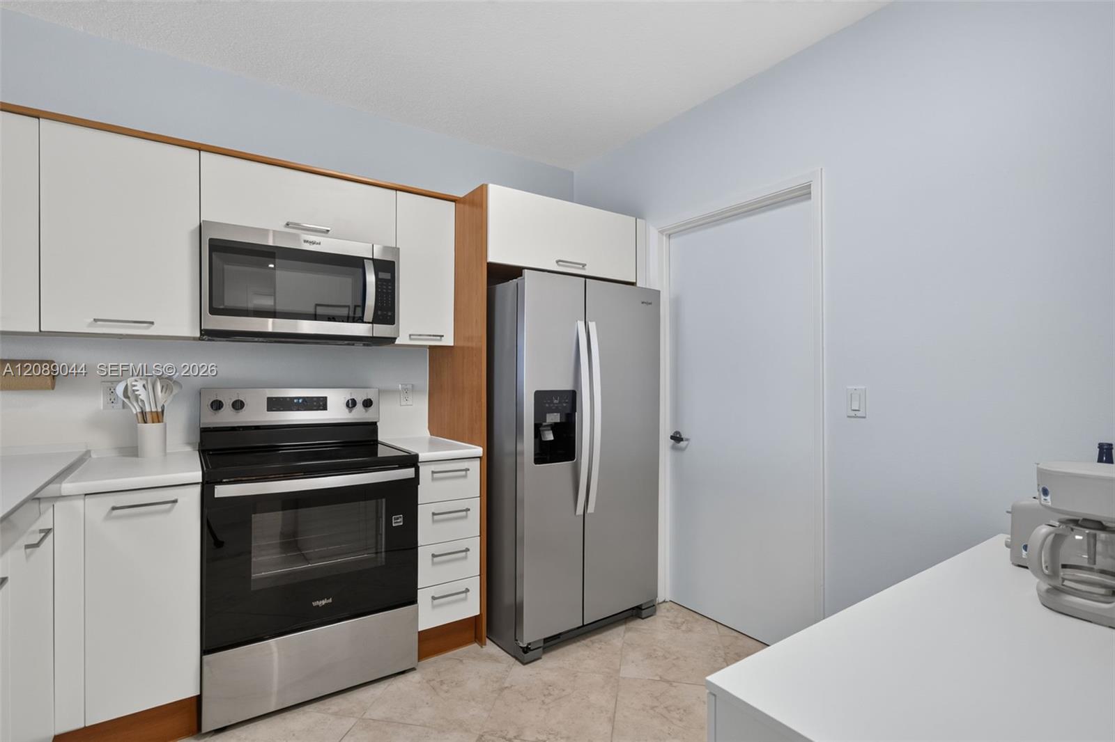 Modern kitchen with white cabinetry, stainless-steel appliances, and a side-by-side refrigerator.