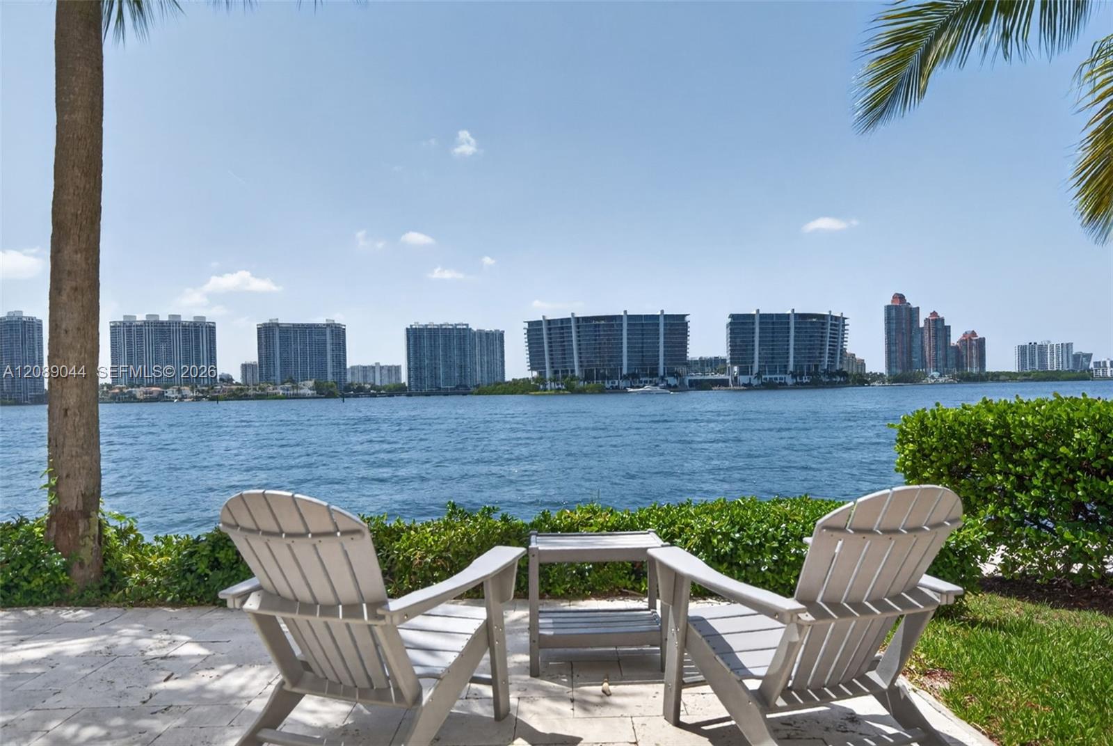 Waterfront patio with Adirondack chairs overlooking the bay and distant skyline.