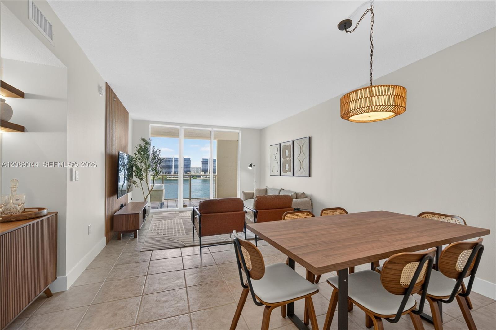 Open-plan living and dining room with a furnished seating area and water views through sliding glass doors.