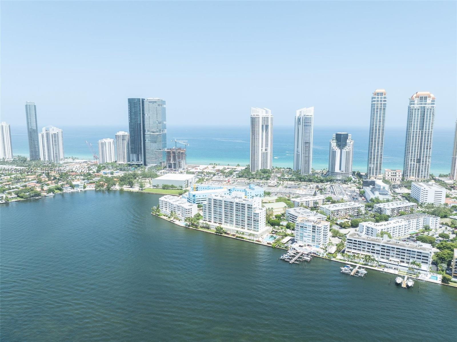 Sunny Isles Beach high-rises along the ocean, with waterfront homes and docks on the bay in front.