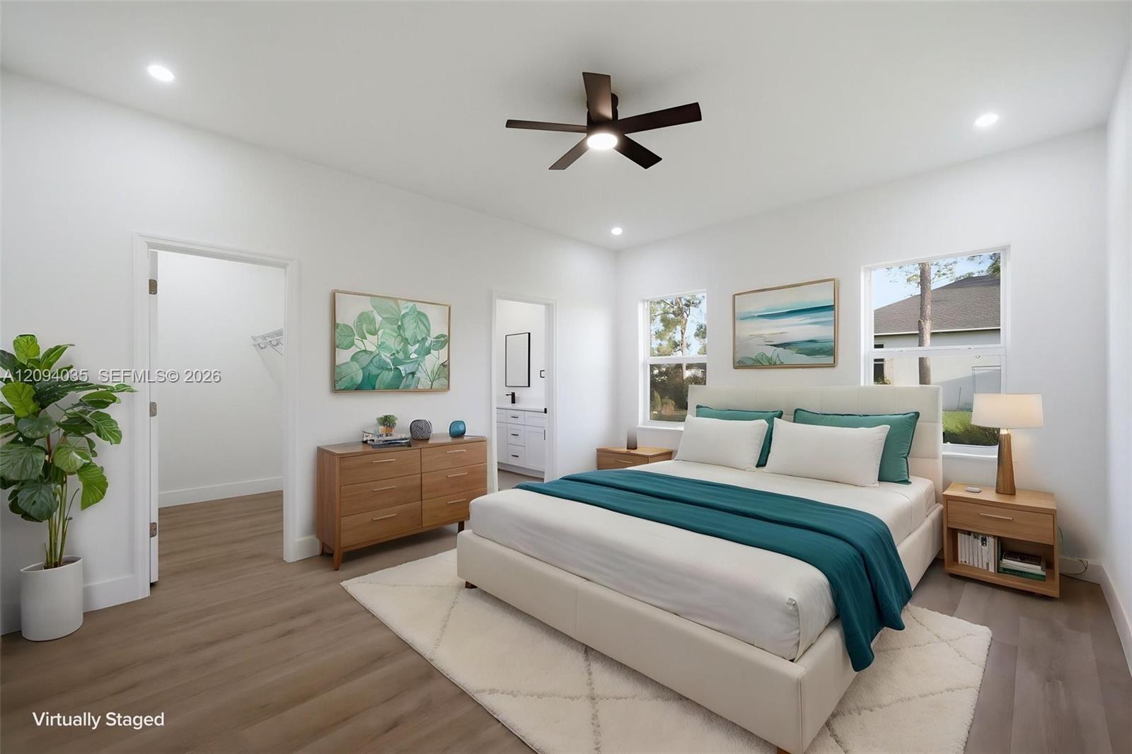 Virtually staged bedroom with a white bed, teal bedding, wood furniture, and two windows.