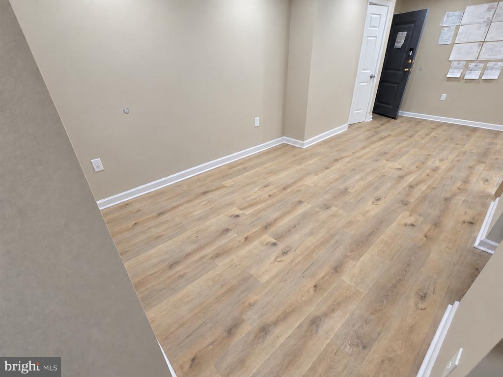 Vacant room with light wood-look flooring, beige walls, and two entry doors.