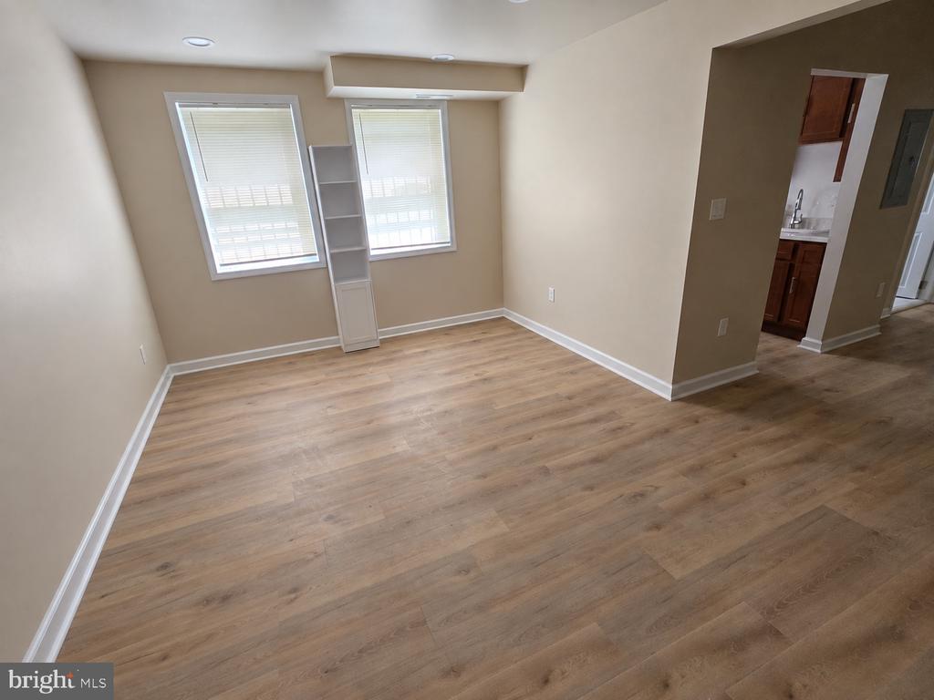 Empty room with wood-look flooring, two blinded windows, and built-in shelving.