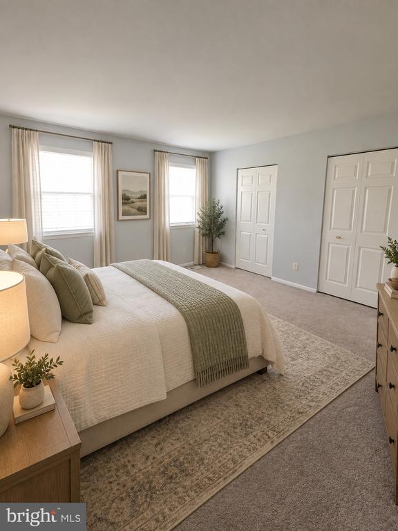 Furnished bedroom with a cream bed, sage-green throw, patterned rug, and two curtained windows.