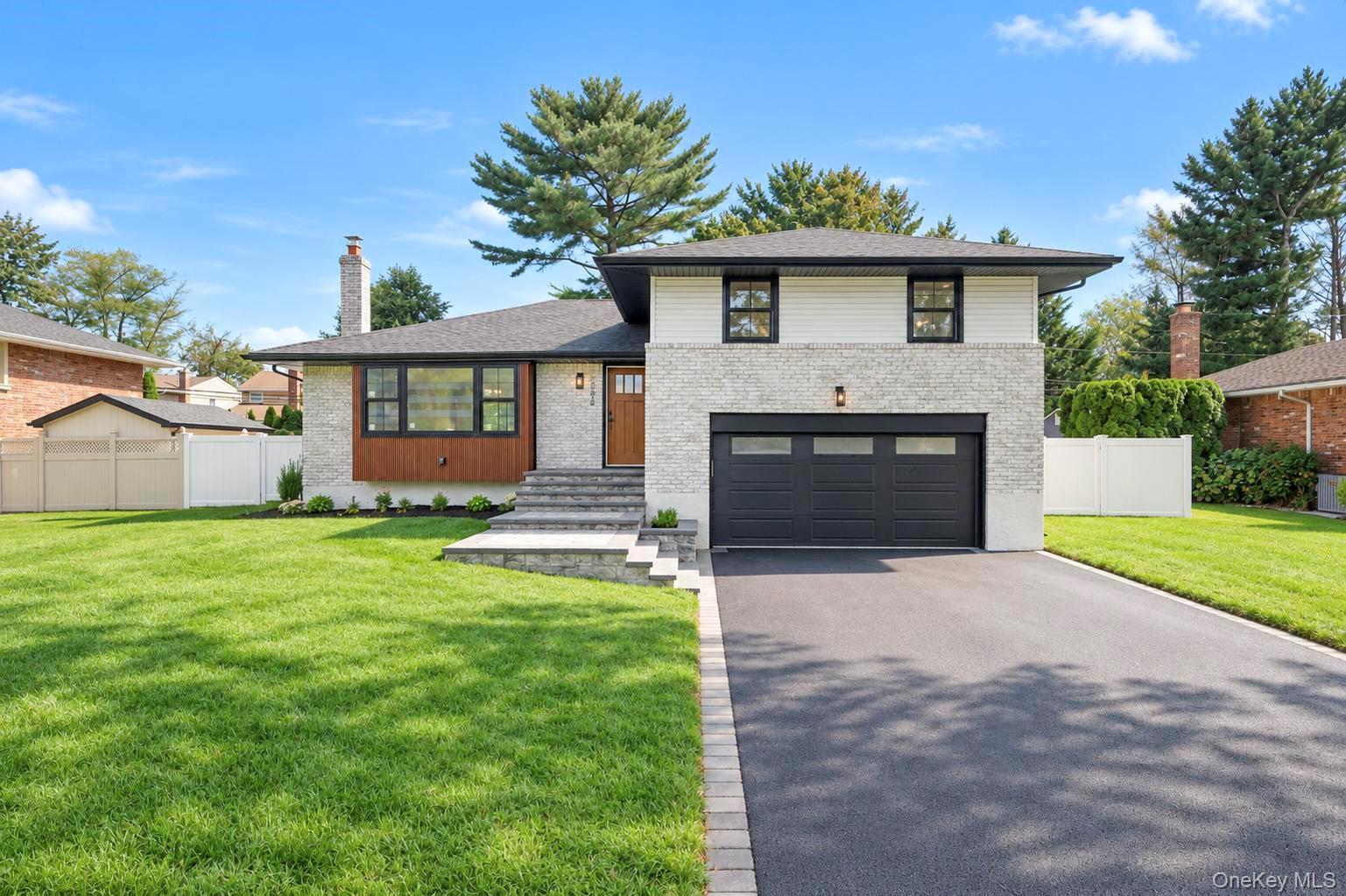 Two-story light-brick home with a black garage door, front steps, and a broad green lawn.
