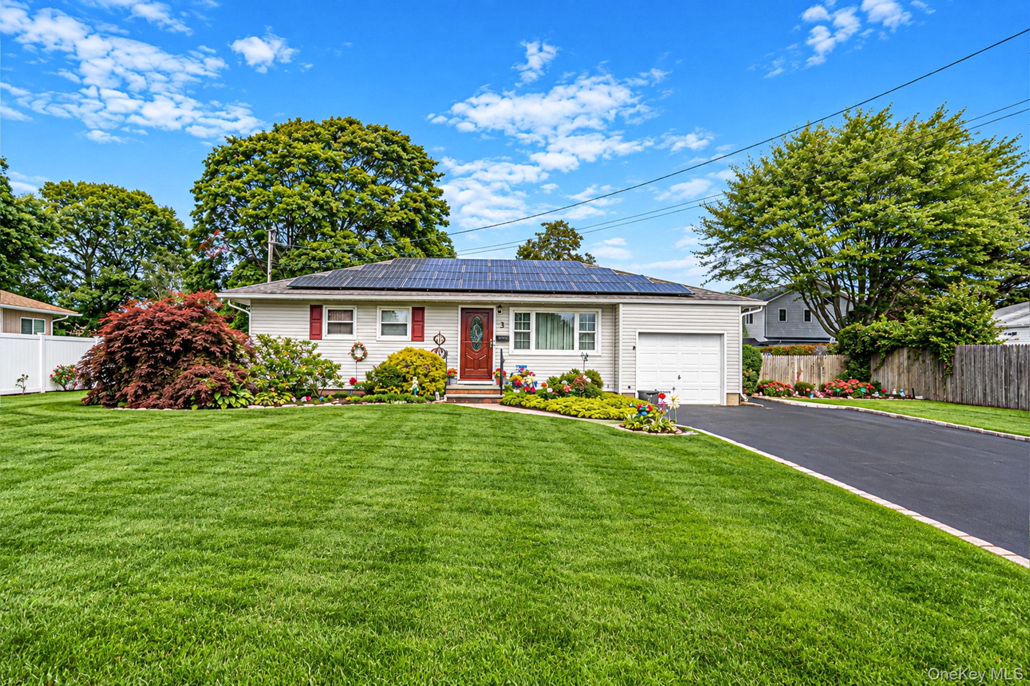 Single-story white house with rooftop solar panels, red shutters, an attached garage, and a landscaped lawn.