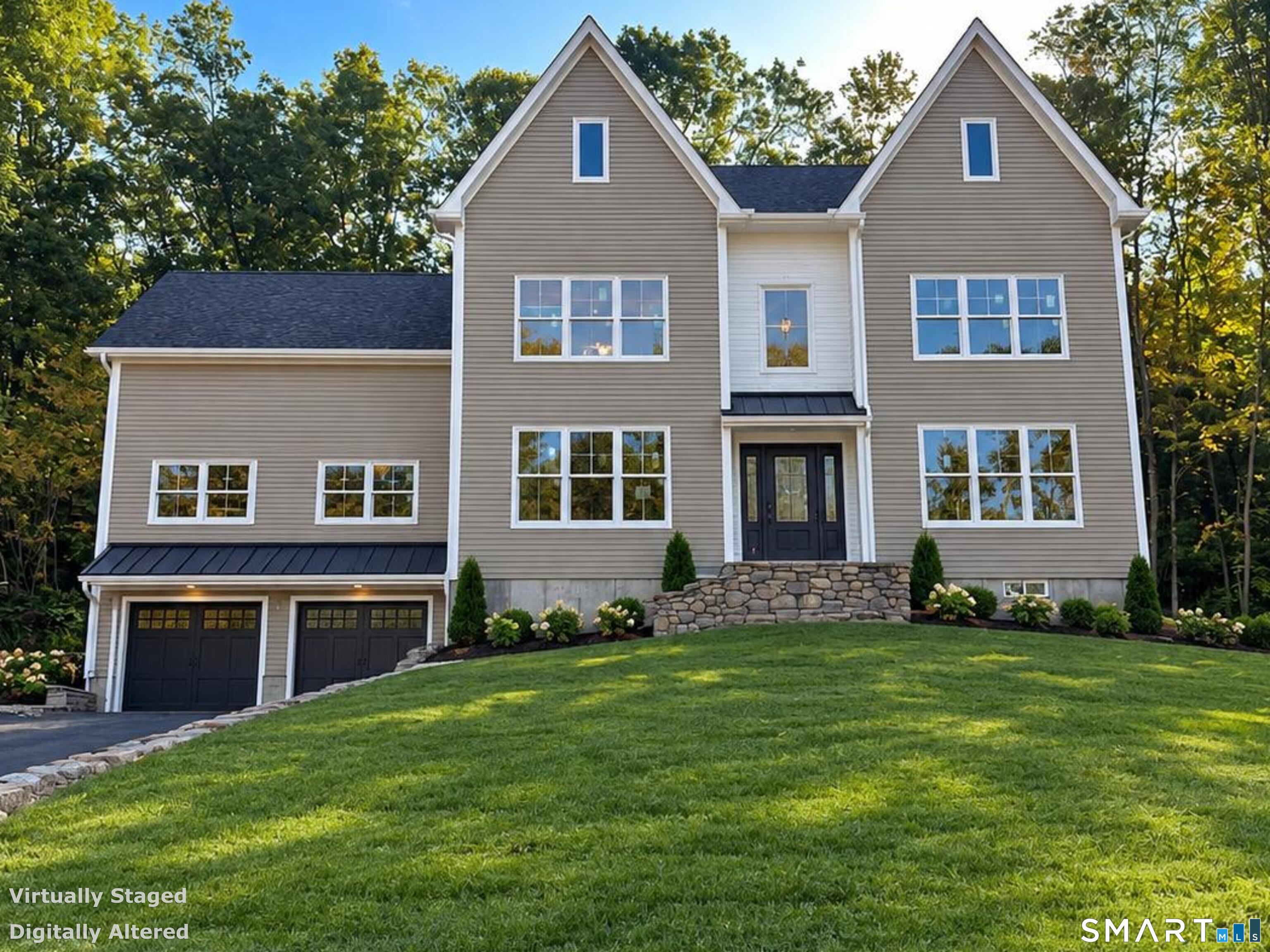 Two-story taupe house with twin gables, a central entrance, and a two-car garage above a sloping lawn.