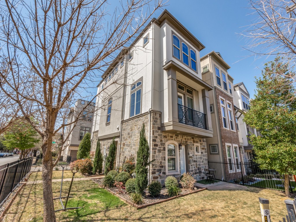 Multi-story townhouse with stone and brick facade, upper windows, and a small balcony.