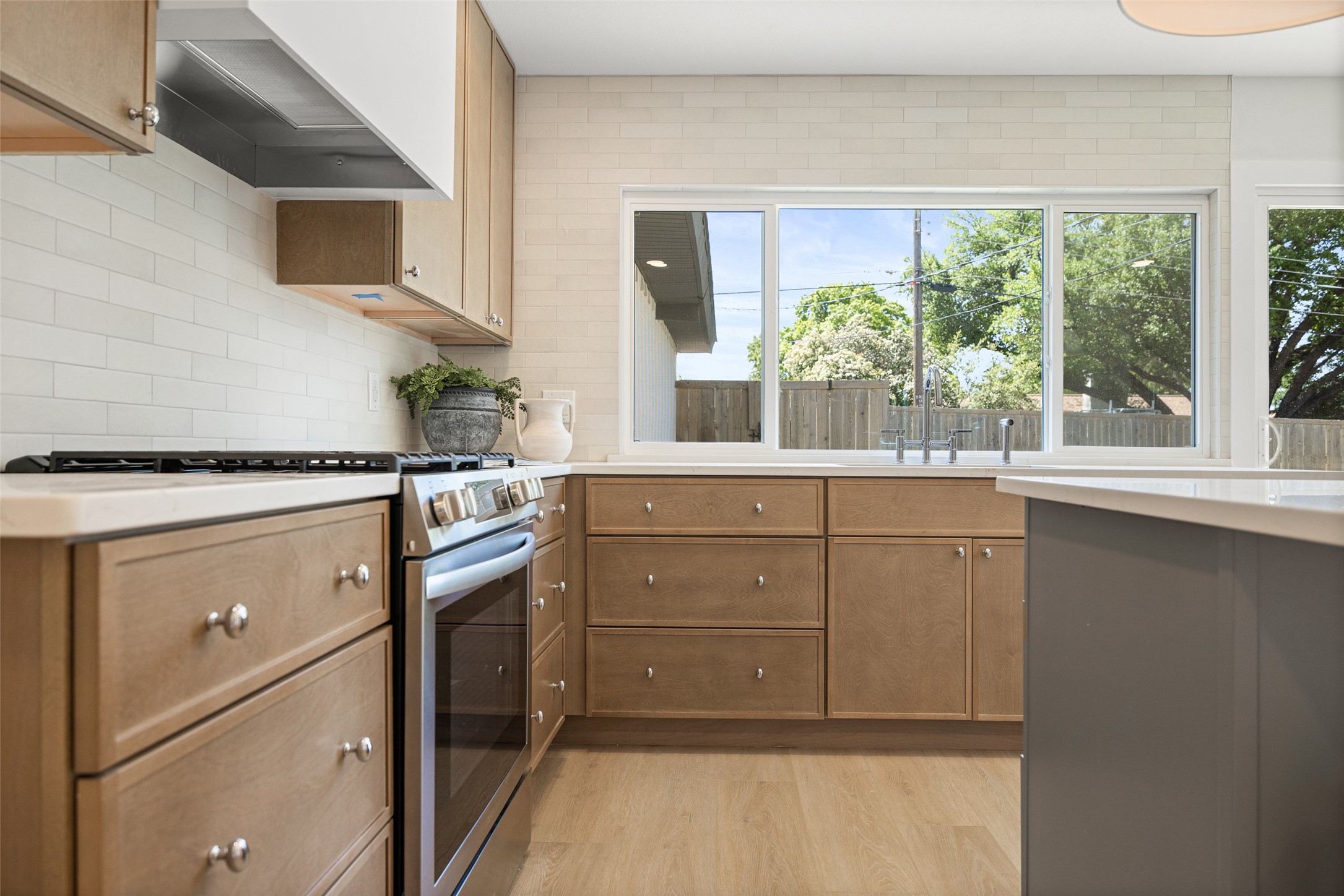 Kitchen with warm wood cabinets, a stainless-steel range, and a large window above the sink.