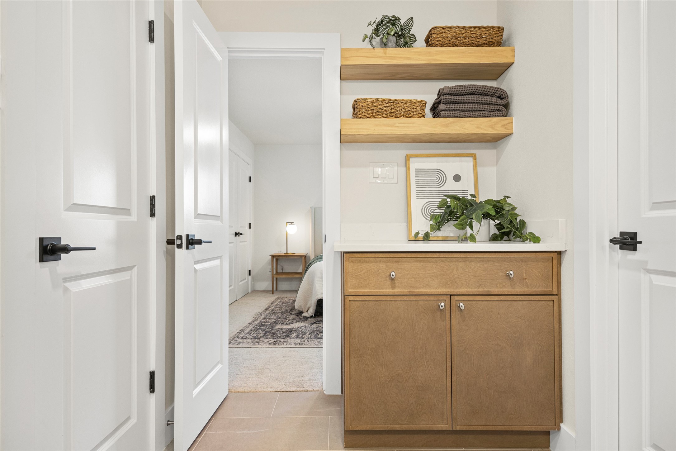 Built-in wood cabinet with floating shelves beside an open doorway to a bedroom.