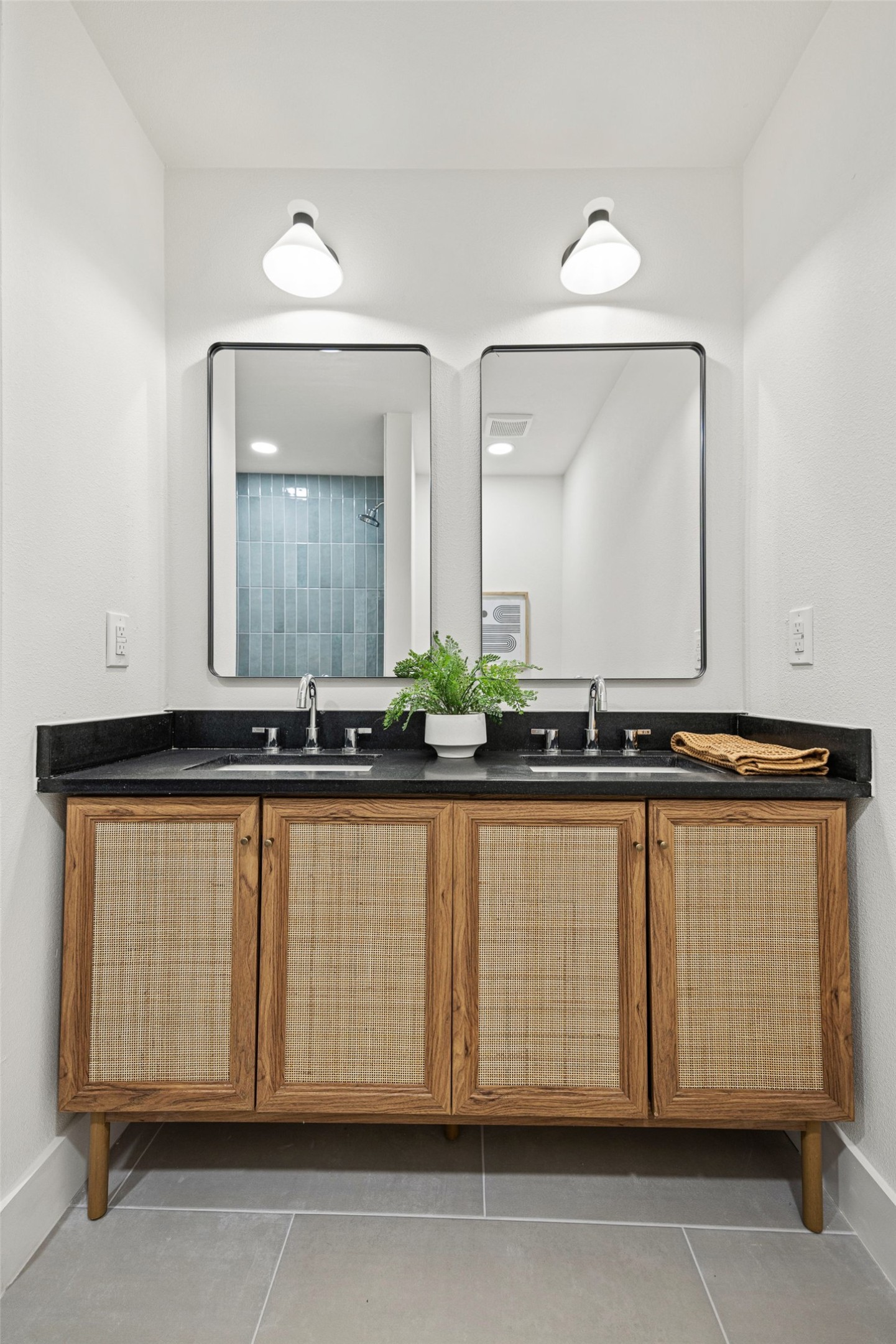 Bathroom vanity with double sinks, woven cane cabinet fronts, and paired mirrors.