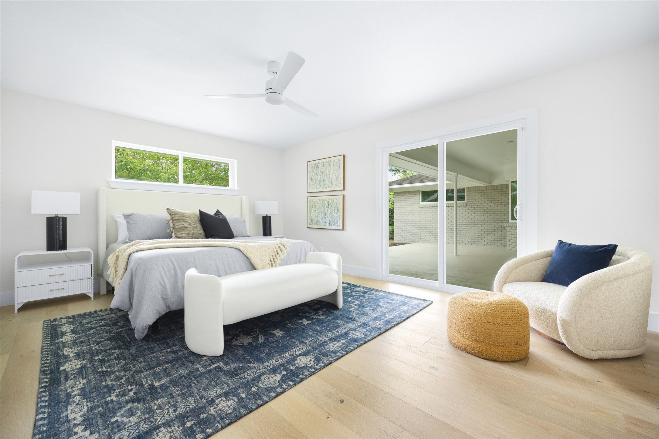 Staged bedroom with a gray bed, blue patterned rug, and sliding glass doors to a covered patio.