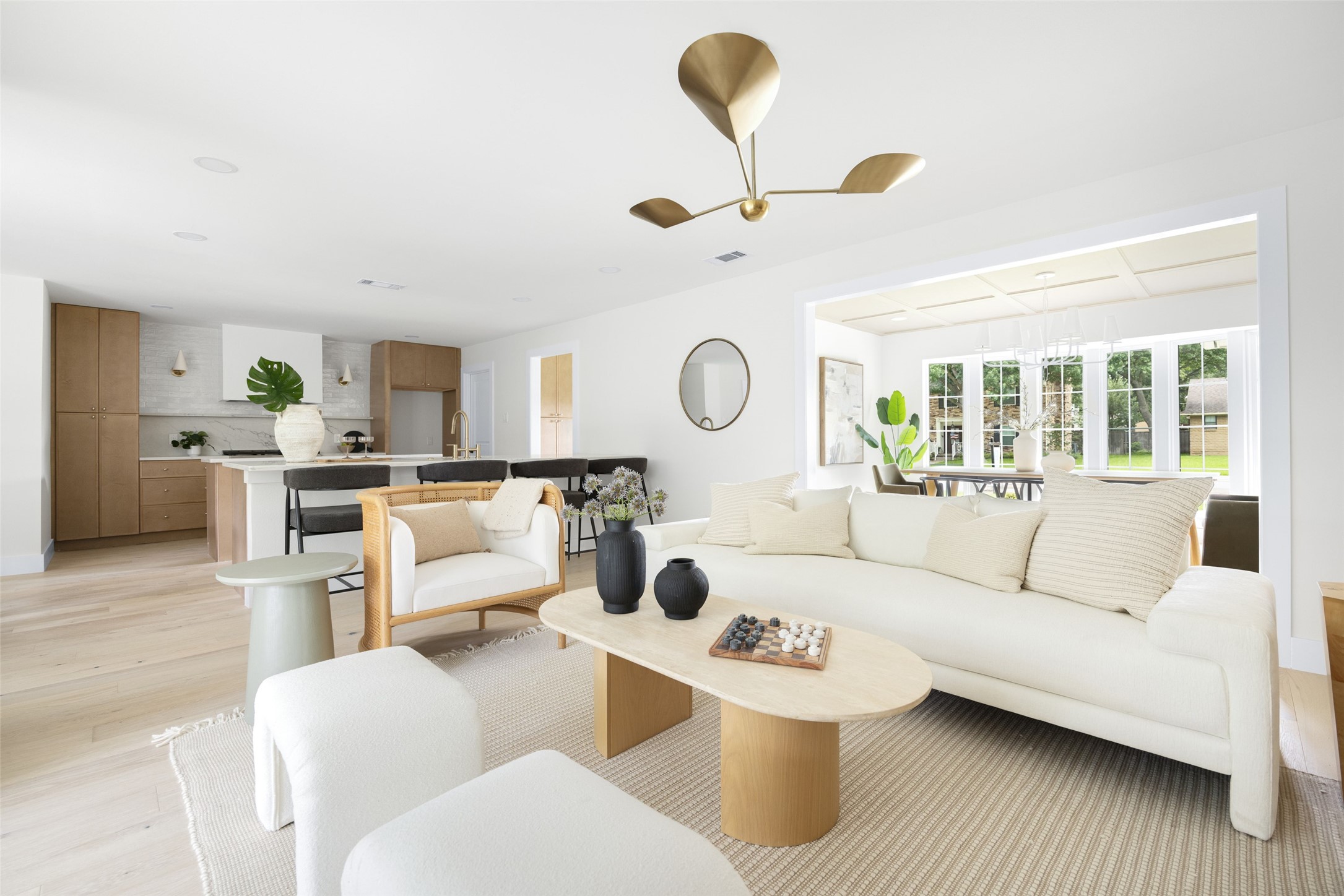 Open-plan living room with a white sectional, wood coffee table, and kitchen beyond.