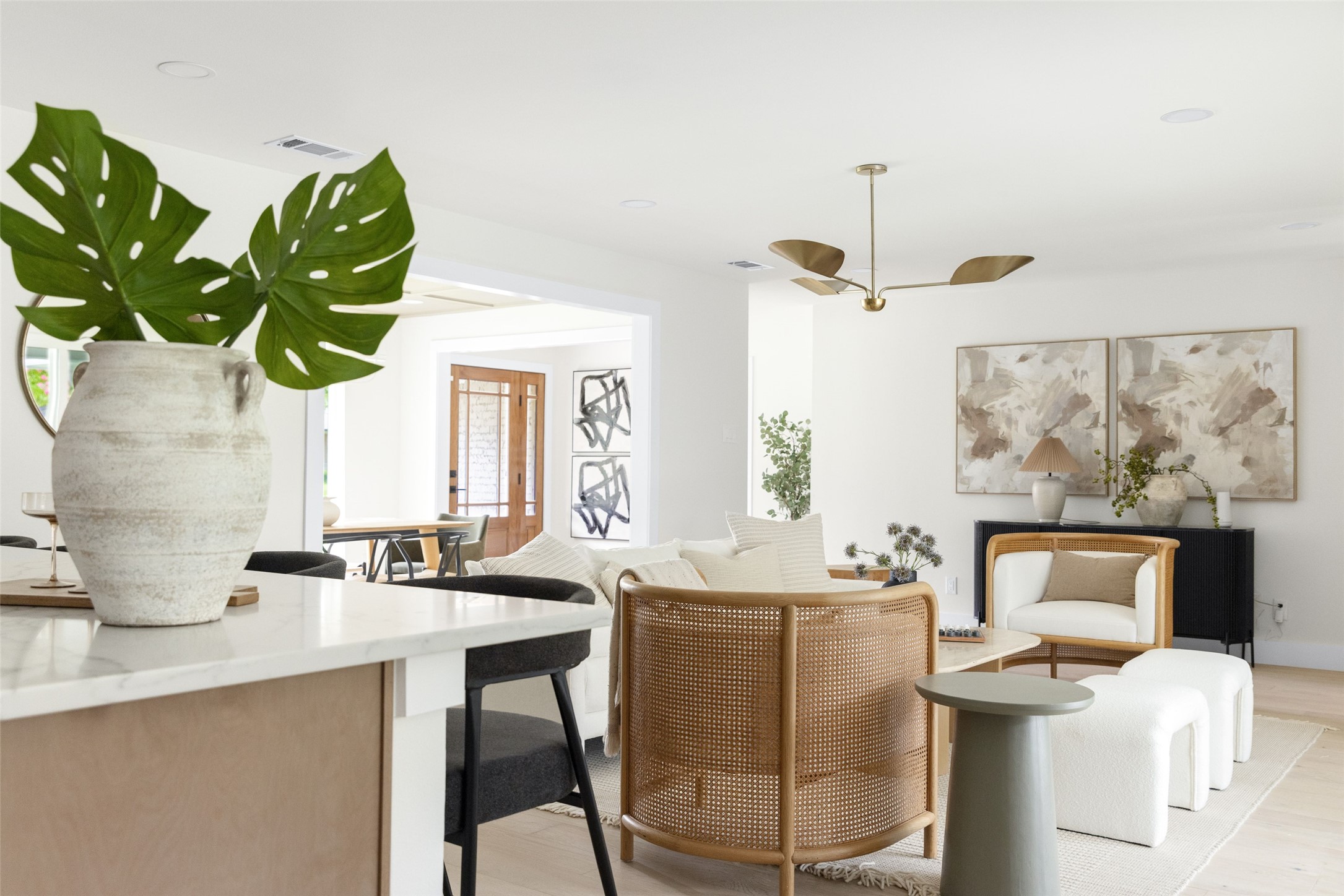 Bright living room with white seating, a cane-back chair, and an open view to the dining area.