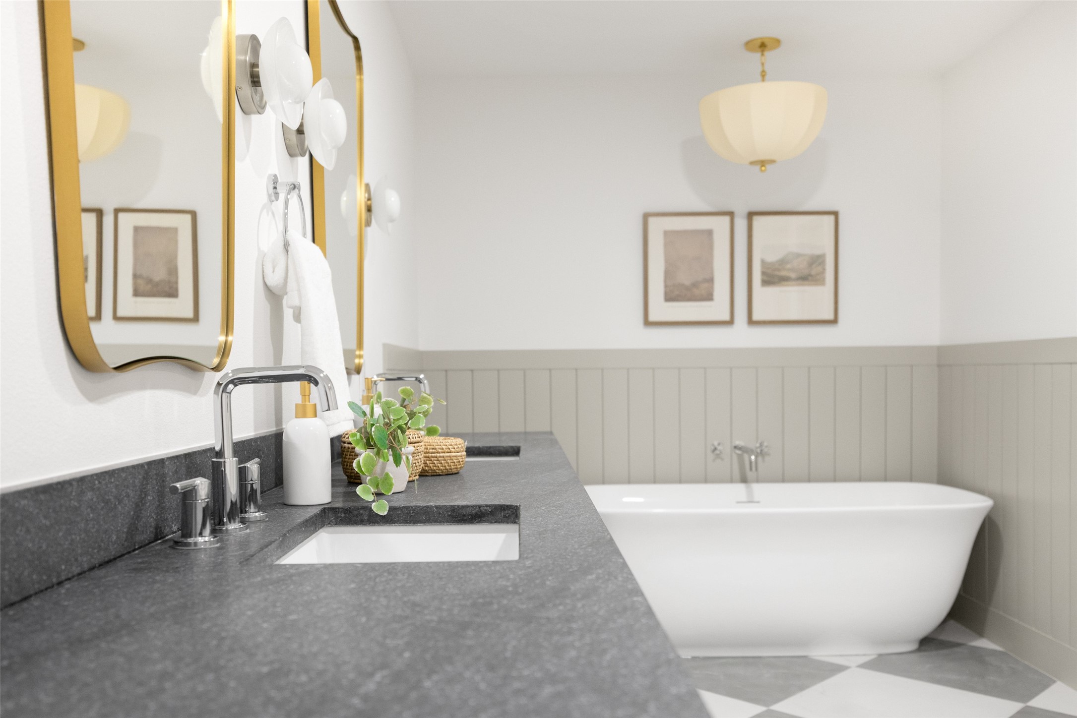 Bathroom with a freestanding tub, gray stone vanity, and gold-framed mirrors.