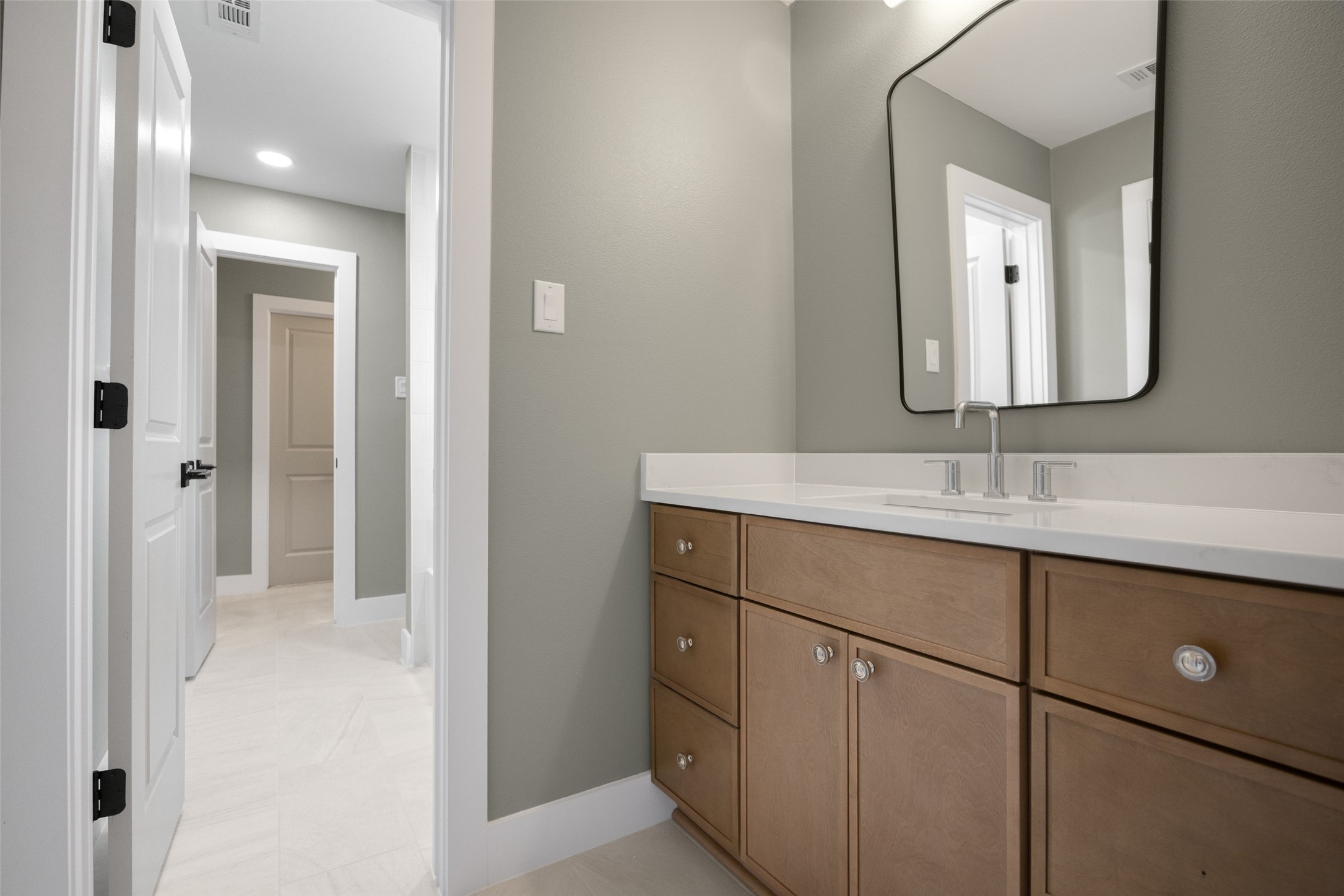 Bathroom with a long wood vanity, double sinks, and a large black-framed mirror.