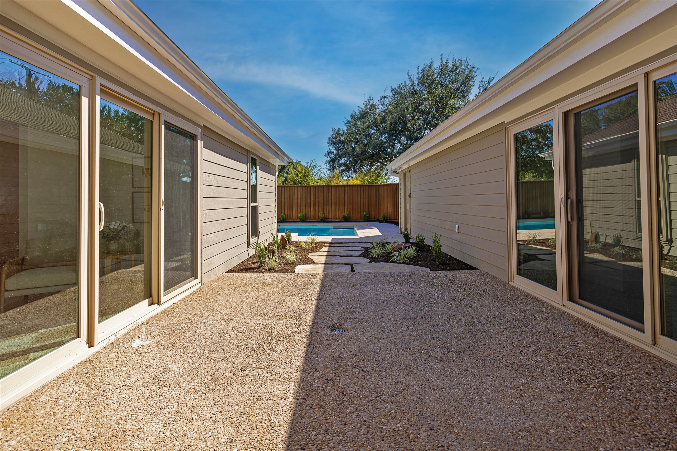 Enclosed courtyard patio with stepping stones leading to a swimming pool between the home’s wings.