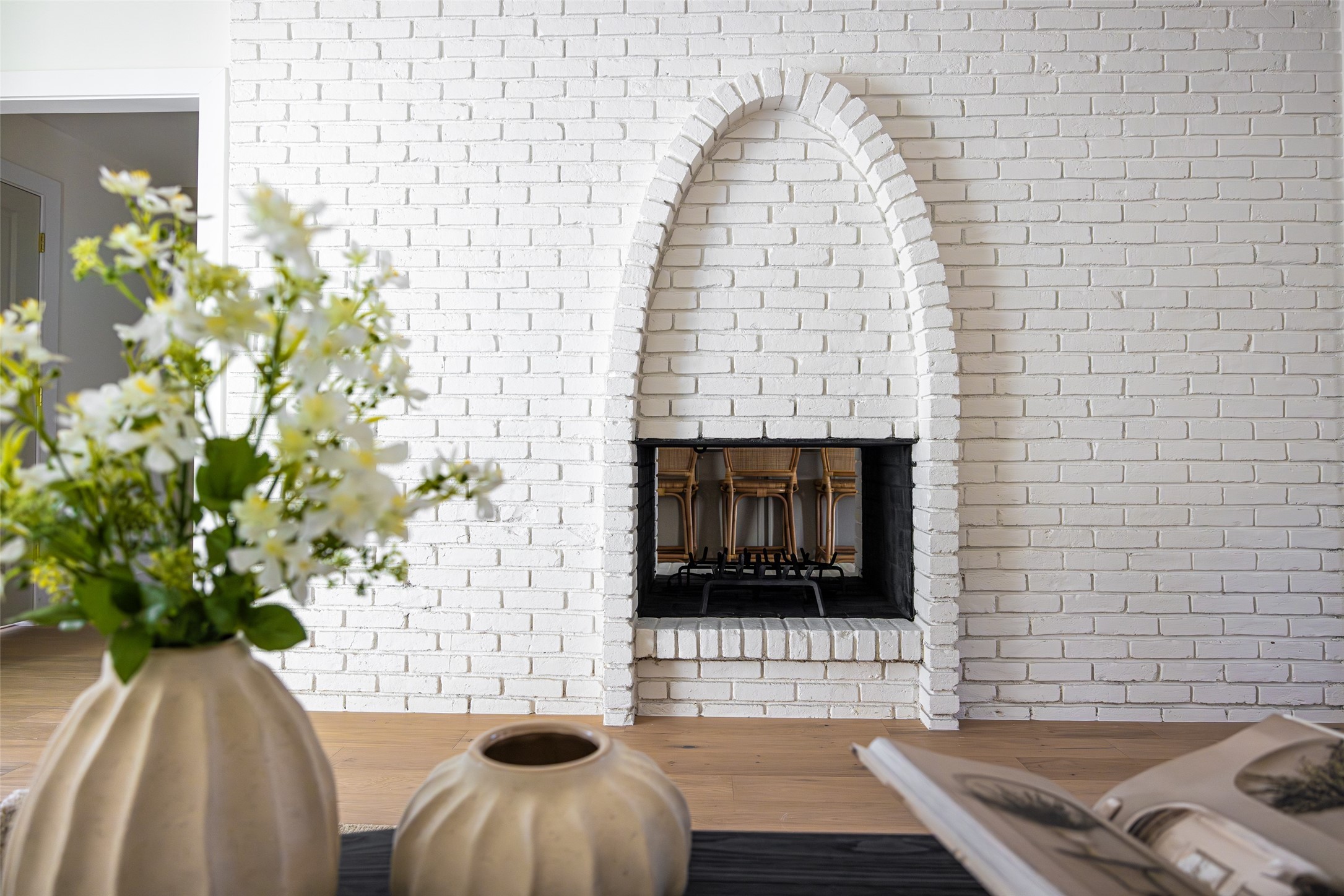 Living room fireplace with an arched white brick surround and chairs visible inside the firebox.