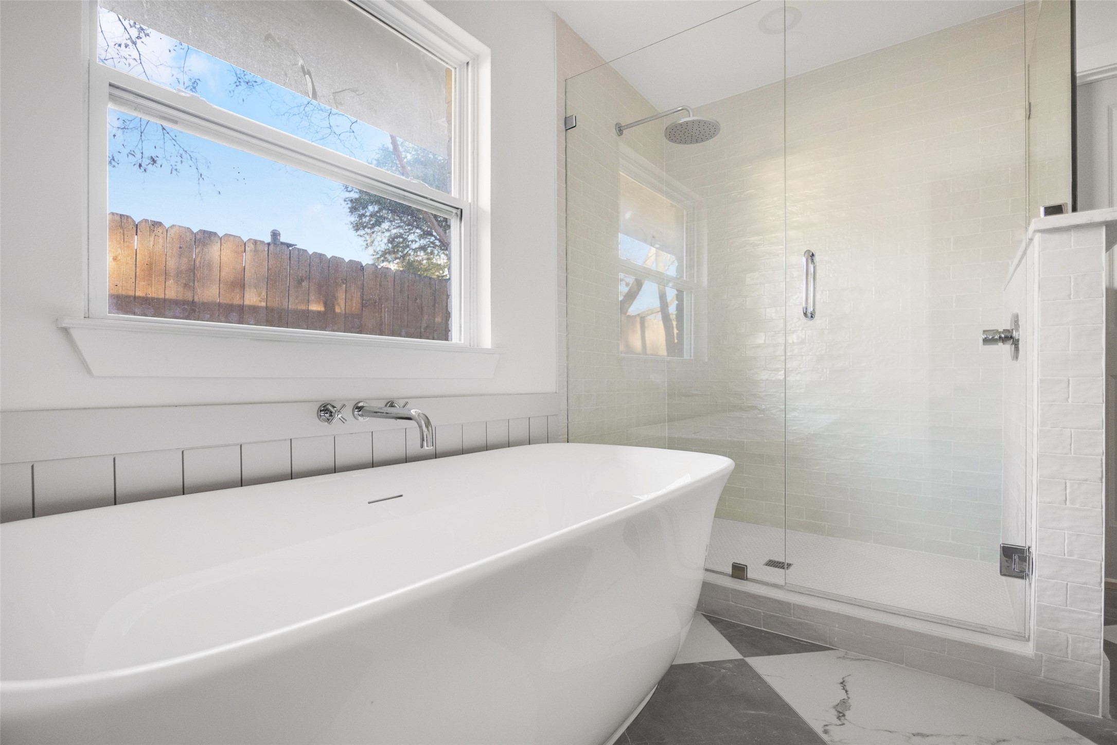 Bathroom with a freestanding soaking tub beside a glass-enclosed tiled shower.