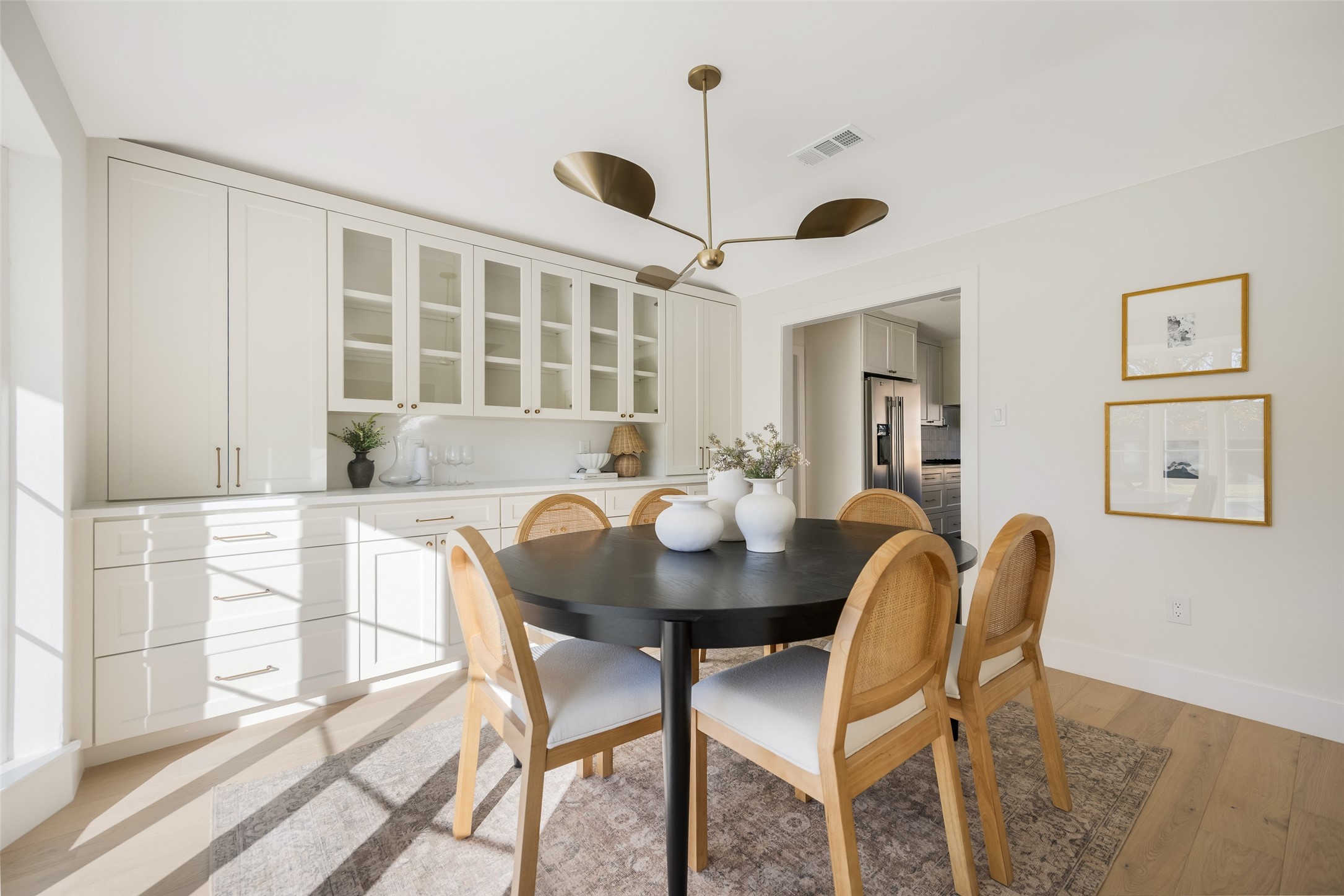 Dining room with a round black table, cane-back chairs, and white built-in cabinetry.