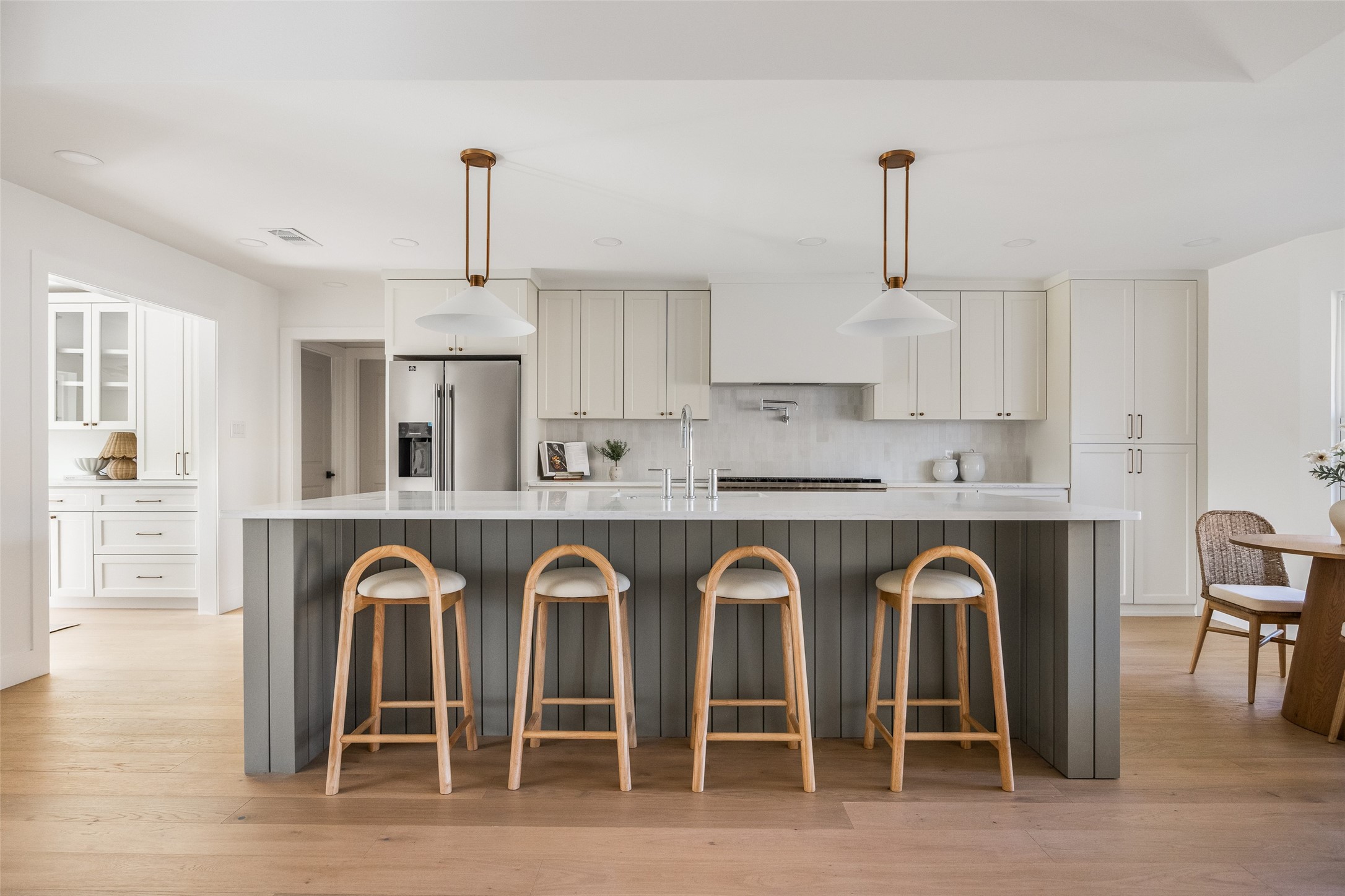 Bright kitchen with a large dark island, white cabinetry, and four wooden bar stools.