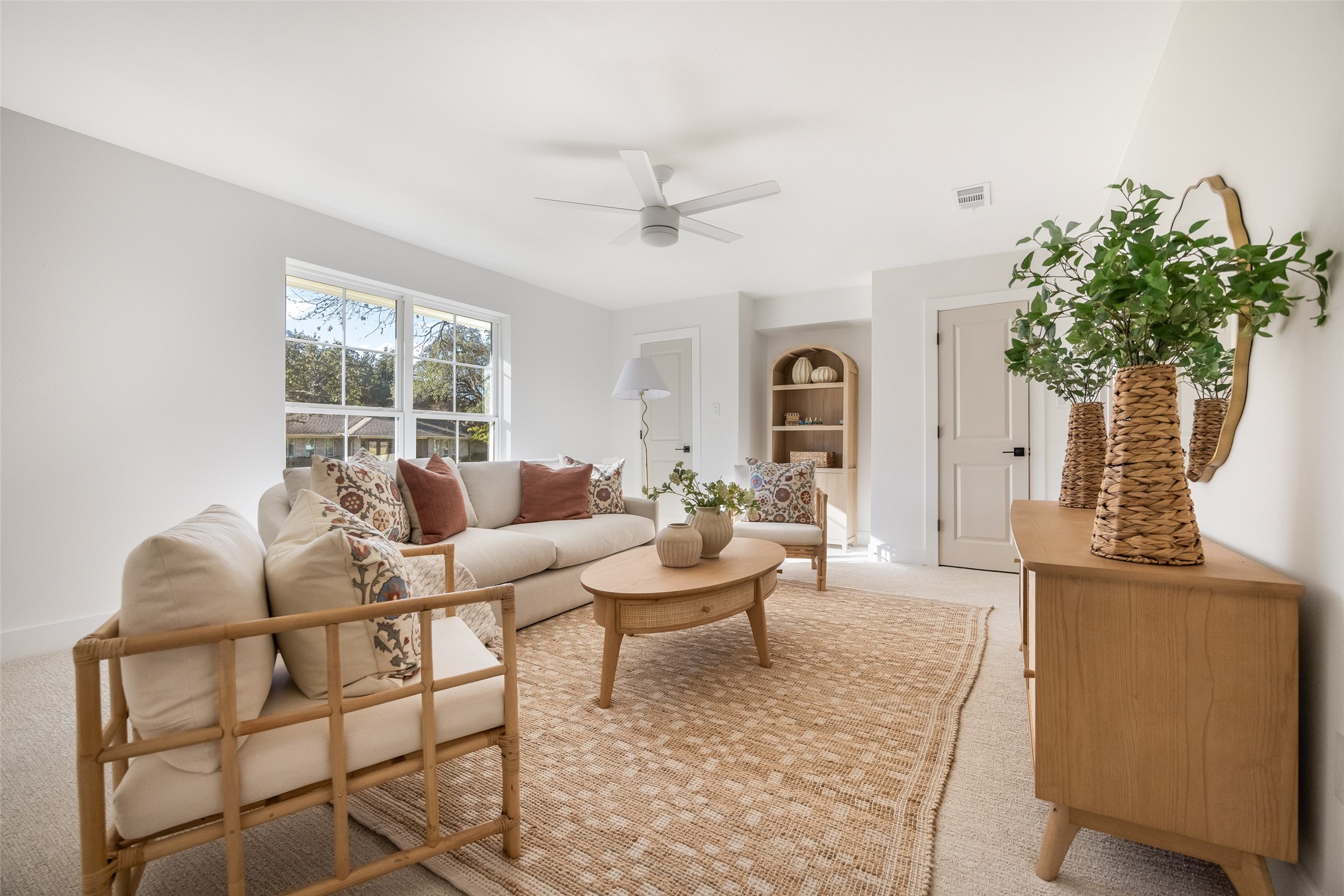 Bright living room with a cream sofa, woven rug, and large windows.