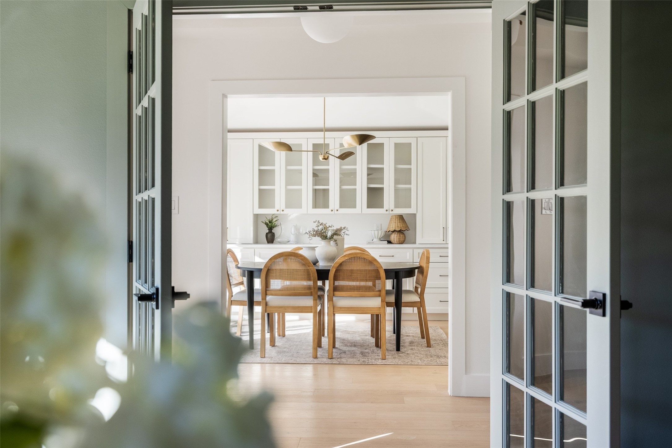 Dining room with woven chairs, a dark table, and white built-in cabinets.