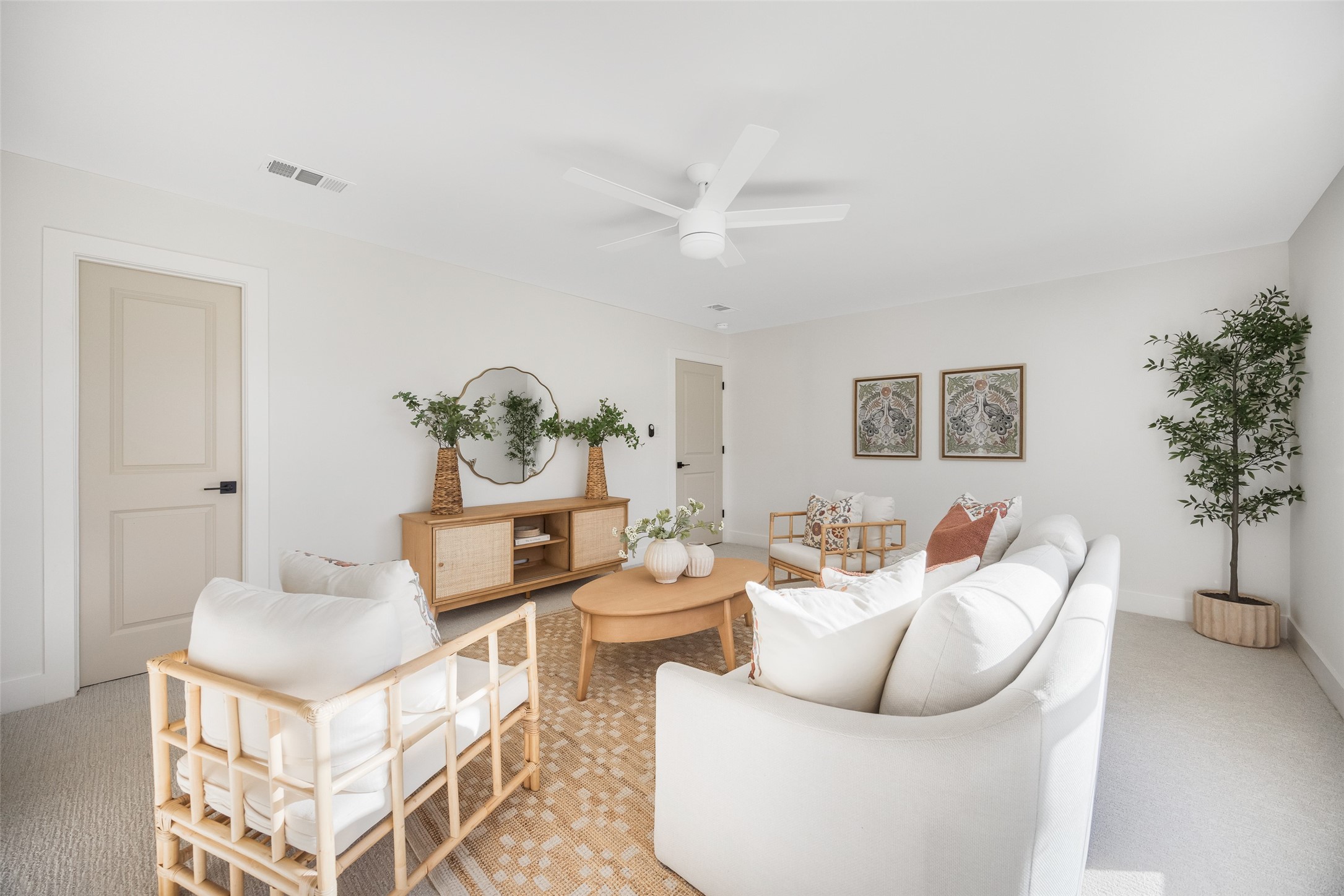 Staged living room with white seating, an oval wood coffee table, and a cane-front console.