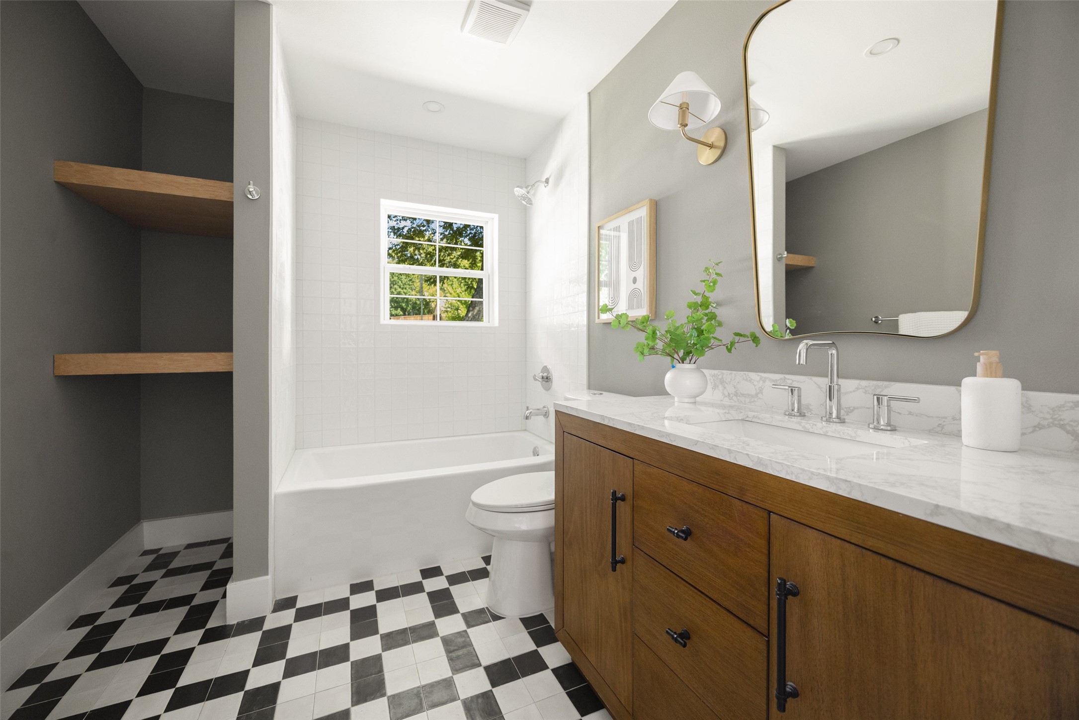 Bathroom with a wood vanity, marble countertop, window above the tub, and checkerboard floor.