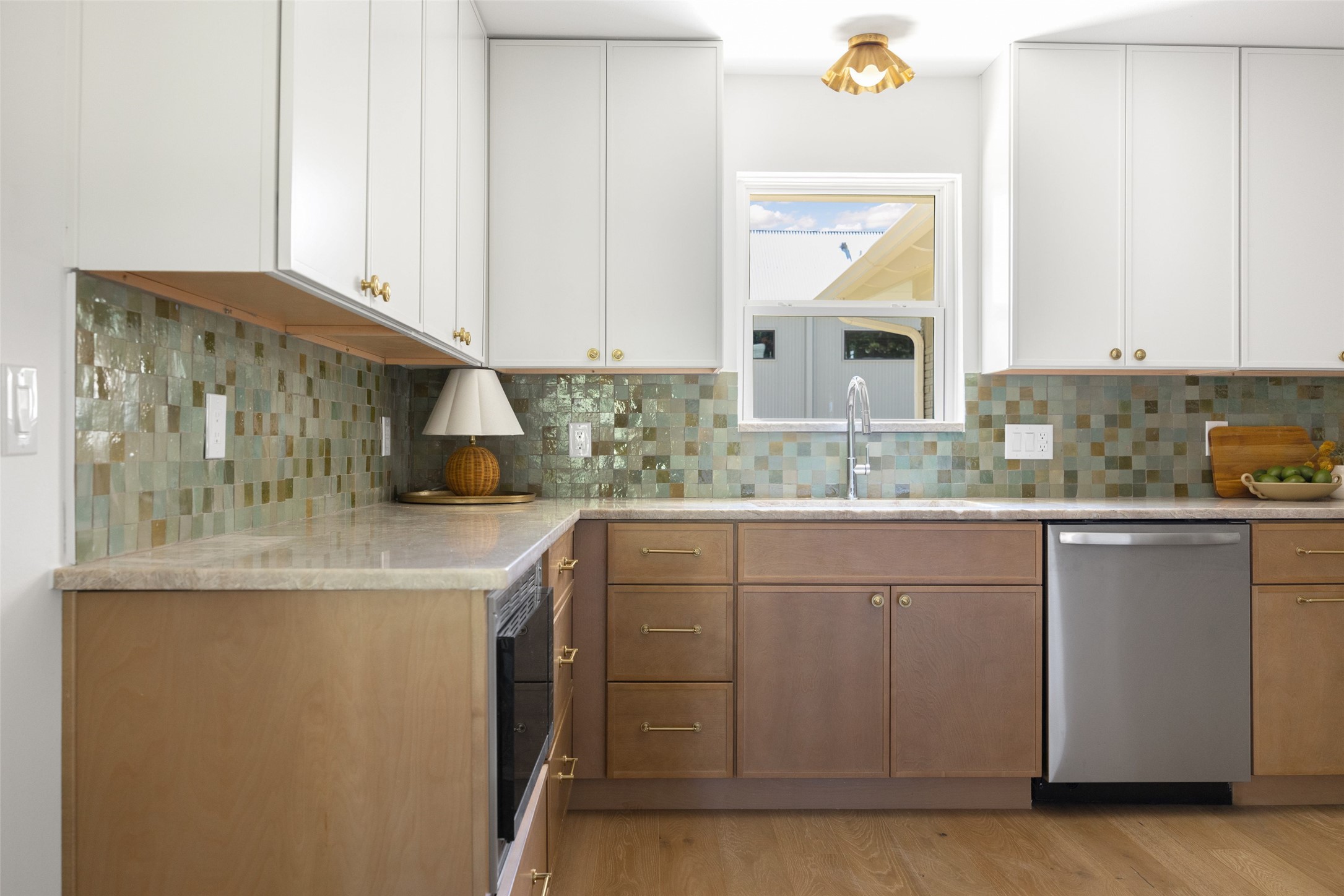 Kitchen with colorful tile backsplash, wood cabinets, and a window above the sink.