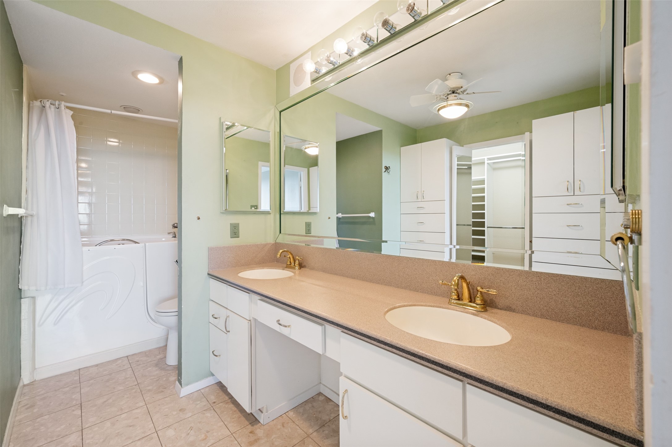 Bathroom with a long double-sink vanity, large mirror, and tub behind a white curtain.