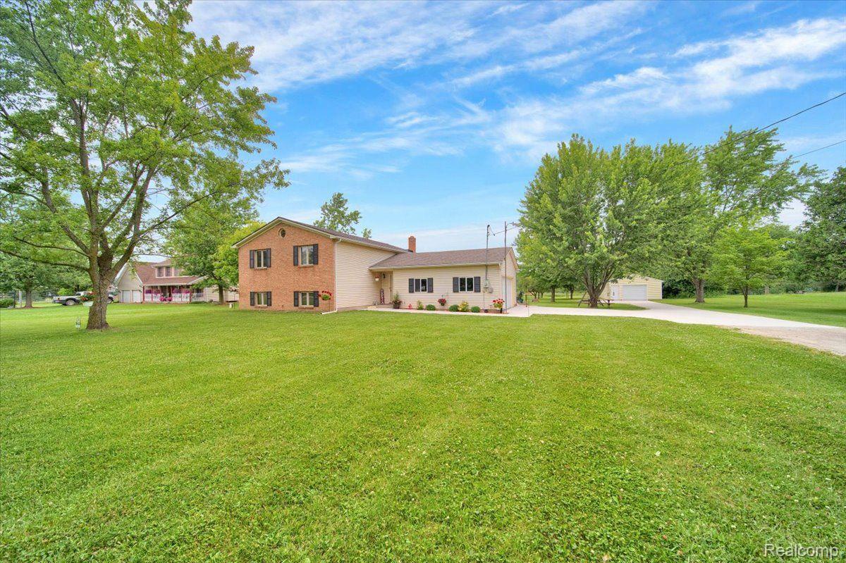 Two-story brick-and-siding home beyond a broad lawn, with a driveway leading to a detached garage.