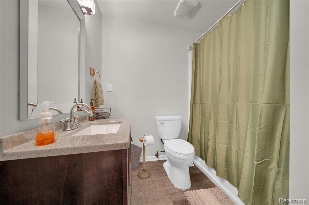 Bathroom with a dark wood vanity, white toilet, and olive-green shower curtain.