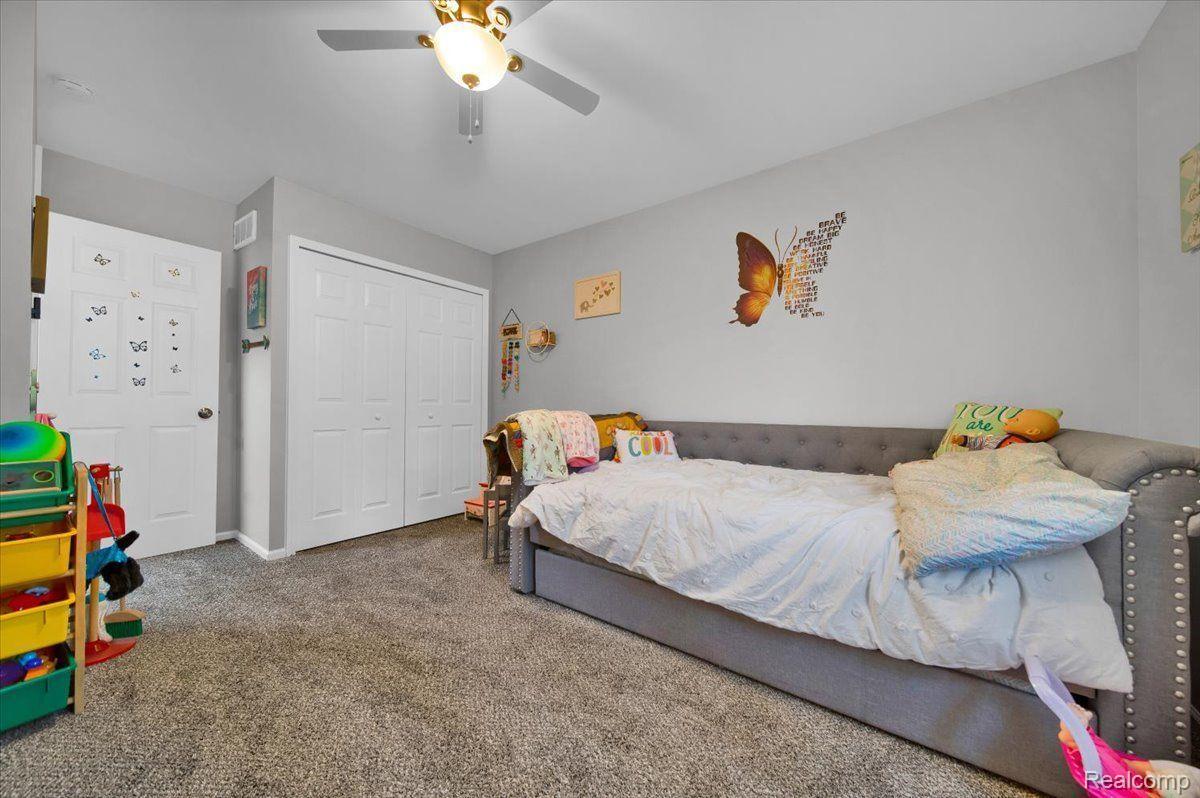 Bedroom with a gray upholstered bed, white bedding, and butterfly wall decor.
