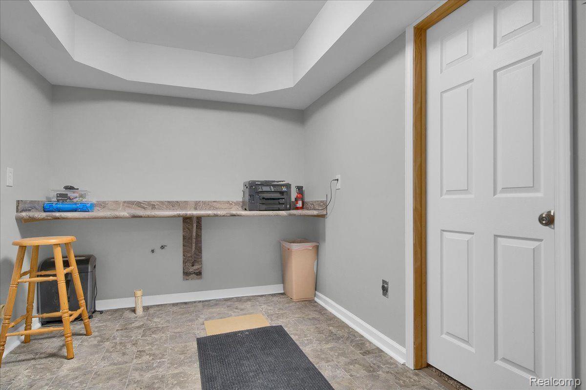 Interior room with a long counter, tiled floor, wooden stool, and white paneled door.