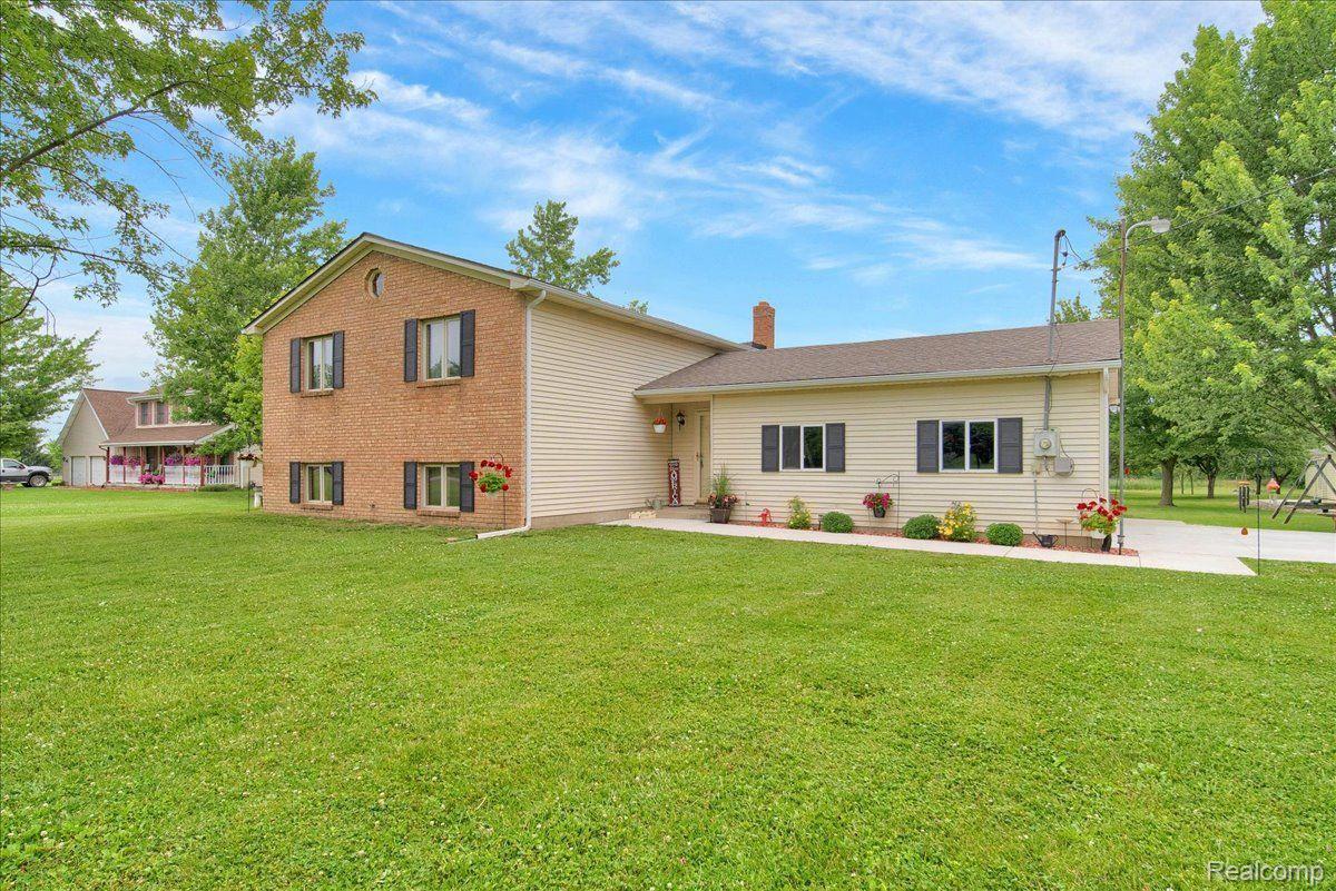 Two-story brick-and-siding home with a broad green lawn and flower beds.