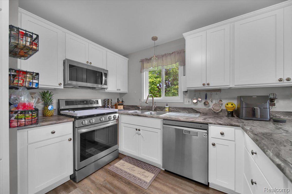 Kitchen with white cabinets, gray countertops, stainless steel appliances, and a window above the sink.