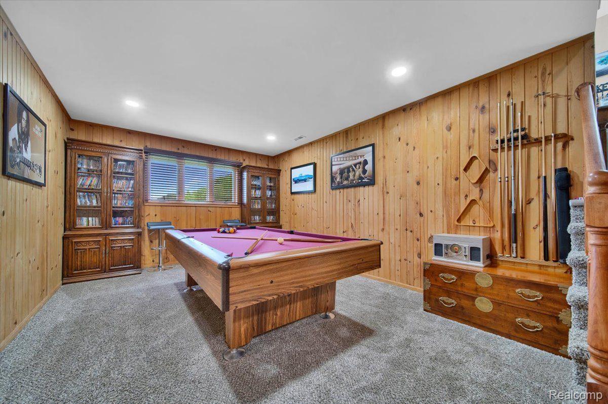 Game room with a purple-felt pool table, wood-paneled walls, and billiard cues.