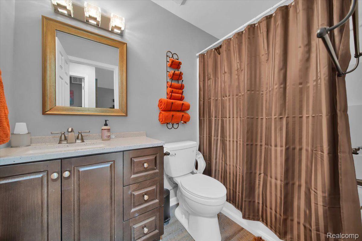 Bathroom with a dark wood vanity, white countertop, toilet, and brown shower curtain.