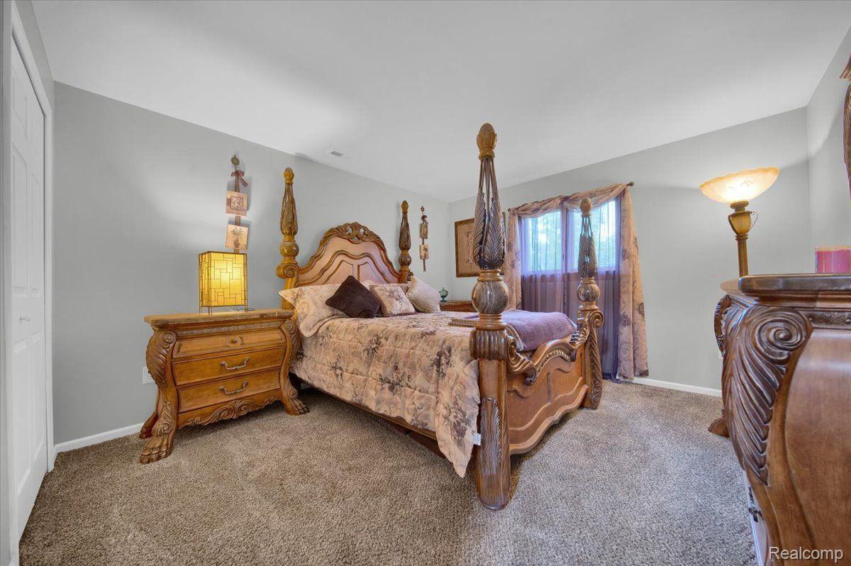 Bedroom with an ornate carved four-poster bed, matching dresser, and beige carpet.