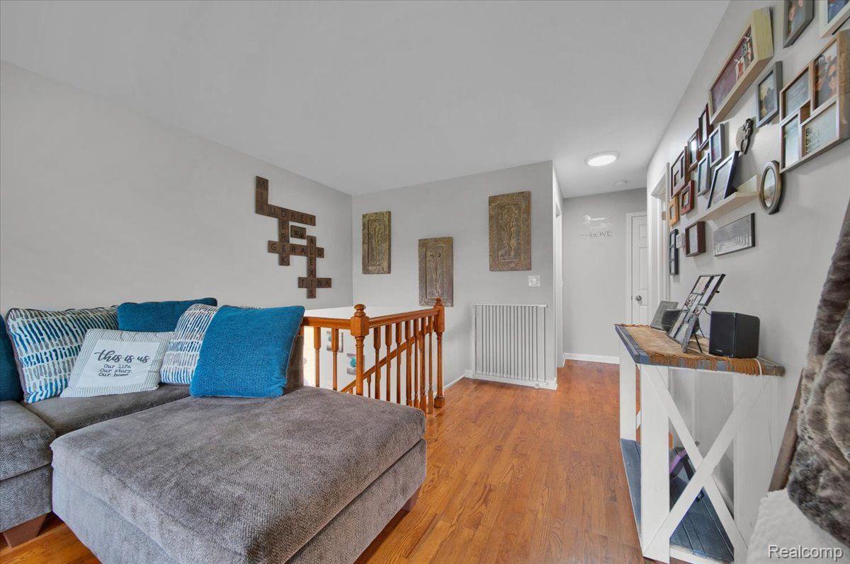 Upstairs sitting area with a gray sectional, blue cushions, and a wooden stair railing.