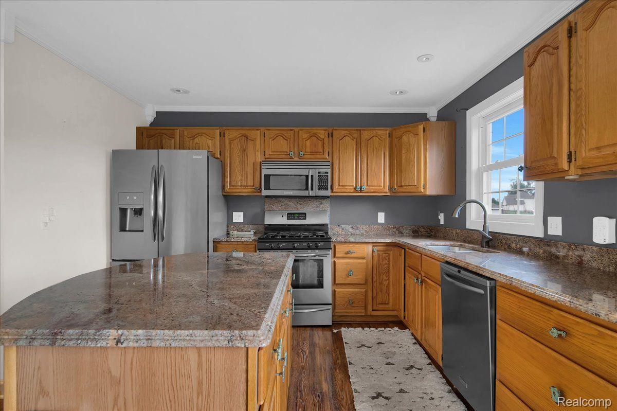 Kitchen with wood cabinets, granite countertops, a large peninsula, and stainless steel appliances.