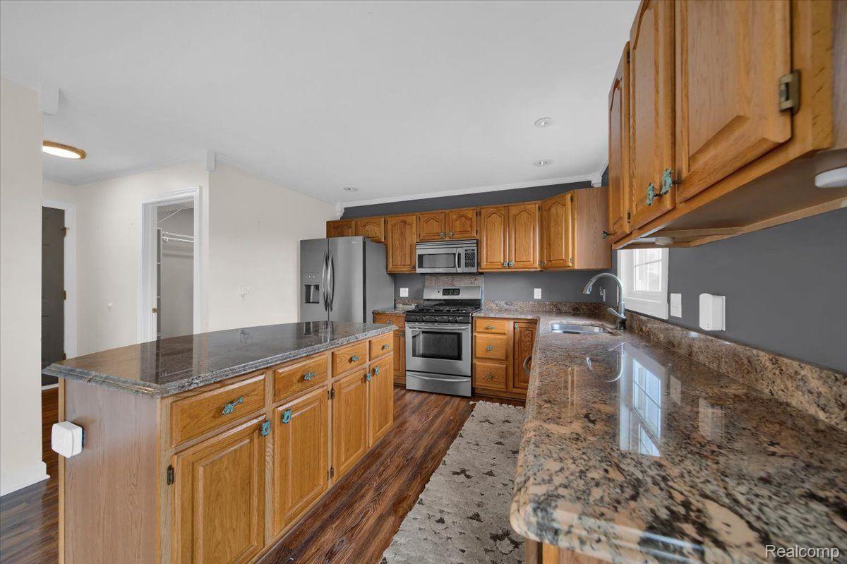 Kitchen with wood cabinets, granite counters, a large island, and stainless steel appliances.
