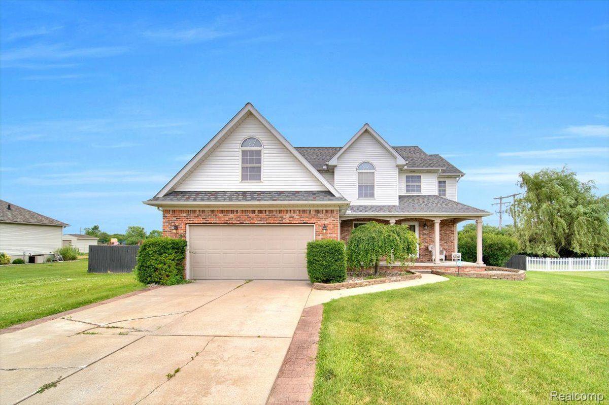 Two-story brick and white-sided home with attached garage, covered porch, and broad concrete driveway.