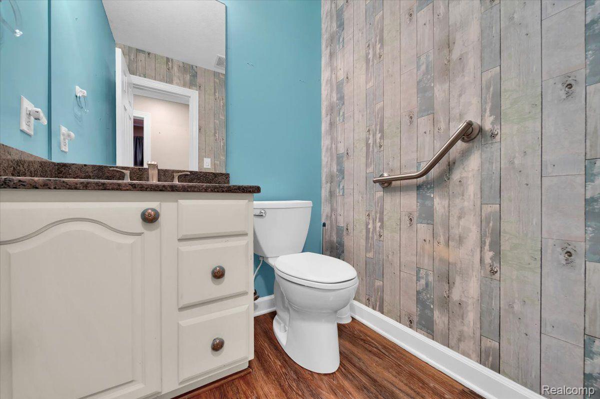 Bathroom with a white vanity, turquoise walls, and a wood-look shower wall with grab bar.